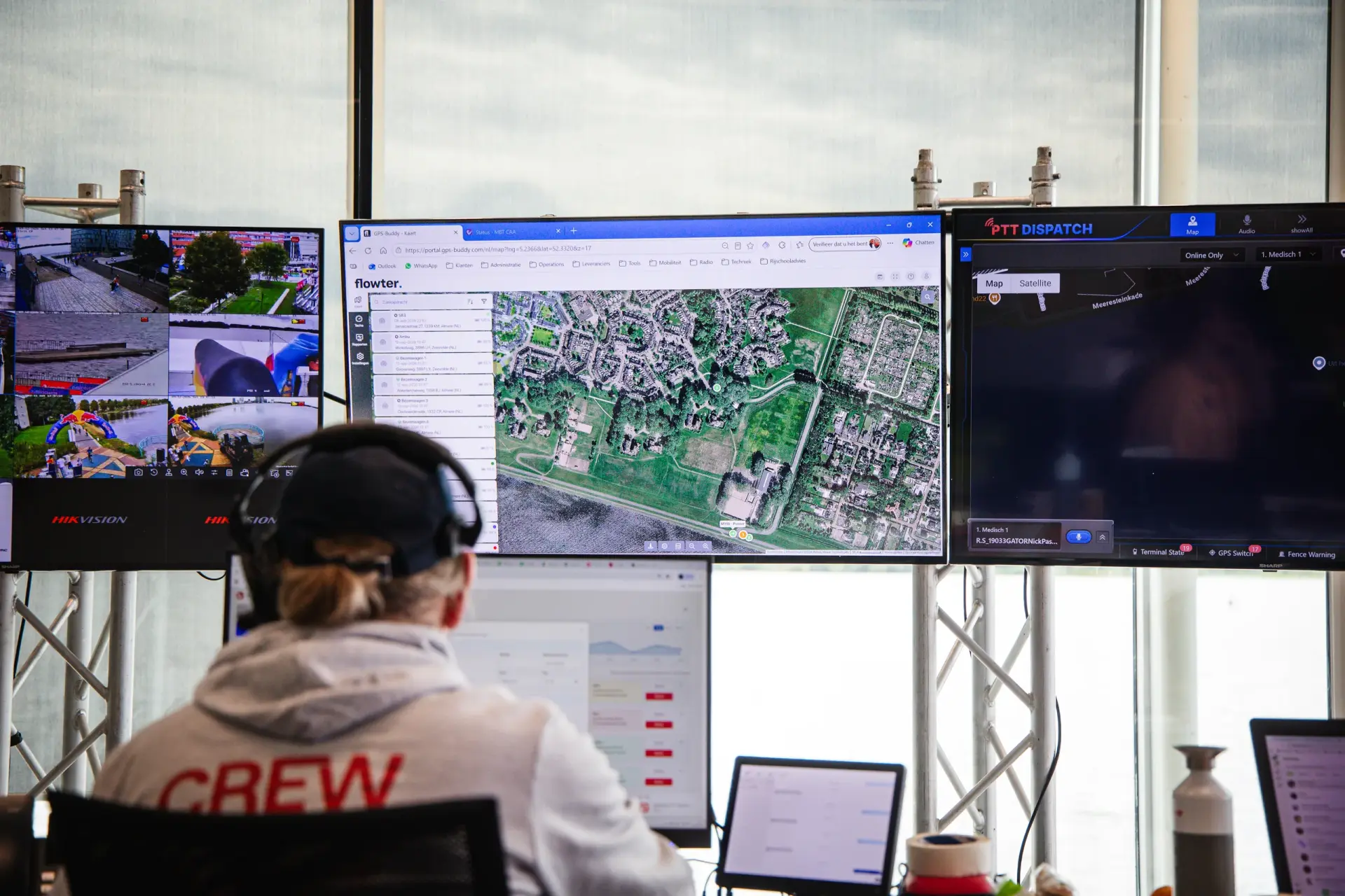 Crewmitglied mit Headset vor Bildschirmen mit Satellitenkarte in Flowter, Kamerabildern und PTT Dispatch