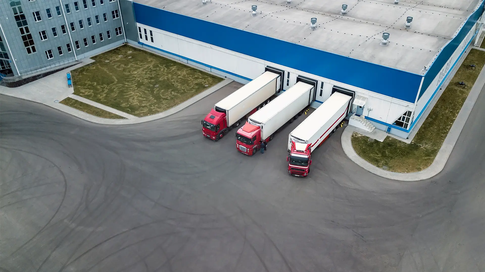 Luchtfoto van drie vrachtwagens die aangekoppeld staan bij de laaddocks van een distributiecentrum